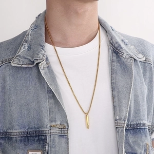 Golden bullet pendant necklace for men with box chain worn by male model over denim jacket