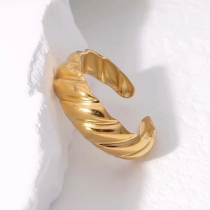 Polished golden stainless steel twisted croissant open ring on a white rock background
