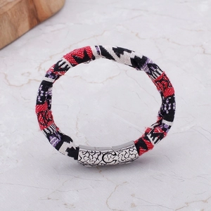 Detailed shot of multi-colored woven cord bracelet with engraved C-shape metal clasp