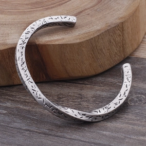Macro shot of retro C-shaped silver stainless steel bracelet with twisted texture detail