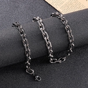 Close-up of industrial silver-toned chunky chain link necklace on a textured black surface