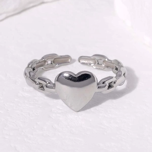 Detailed shot of silver heart ring with chain texture band on marble background
