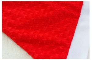 Macro shot of red embossed plush fabric with soft white trim texture on the Christmas hat