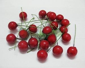 Close-up of glossy red foam heart cake toppers with green stems on white background