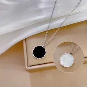 Detail of hexagonal shell pendant on gold necklace over white silk fabric background