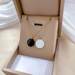 Minimalist hexagonal shell pendants on gold and silver titanium steel necklaces in a box