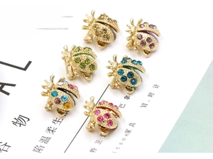 Detail view of colorful rhinestone ladybug brooches in six vintage gold-toned color sets