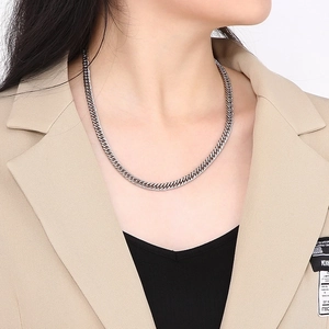 Silver stainless steel cuban curb chain necklace styled on a model in a beige suit