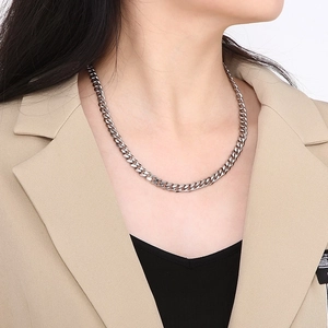 Close-up of polished silver titanium steel Cuban link chain worn by a female model