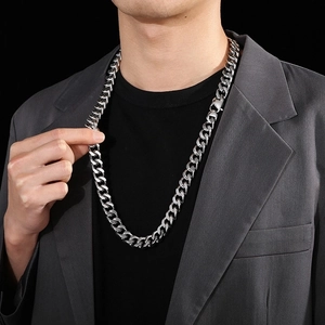 Close-up of 14mm silver Cuban link chain necklace worn by a male model with a suit