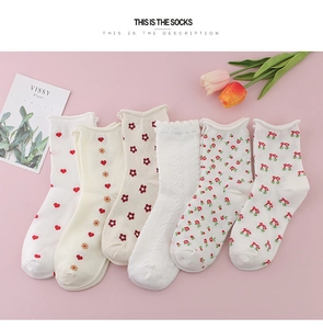Detail view of six pairs of white mid-calf cotton socks with heart and floral patterns