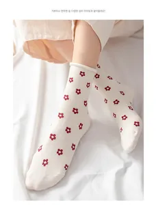 Close-up of cream cotton socks with red floral patterns and rolled edge detail