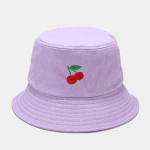 Détail de la broderie cerise sur un bob en coton violet avec coutures de bord renforcées