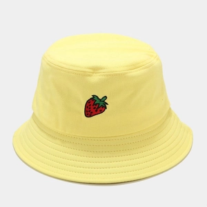 Détail d'un bob en coton jaune avec une broderie de fraise rouge éclatante