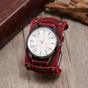 Close-up of retro punk watch with wide red leather strap and rivets on wooden surface