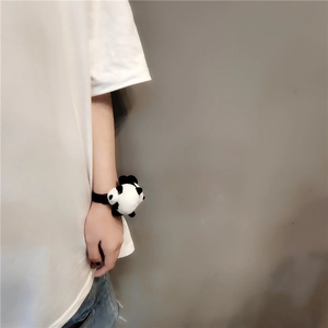 Detail showing a cute plush panda accessory worn on the wrist with soft black and white fur