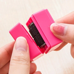 Pink portable privacy roller stamp for identity protection on smooth wooden surface
