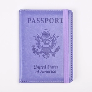 Detalle de funda de pasaporte en cuero púrpura con banda elástica y logo de Estados Unidos