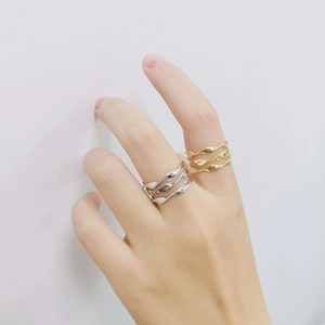 Detail of gold and silver S925 sterling silver triple-layered wavy rings on model finger