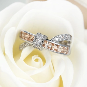 Macro shot of a silver crossover ring with champagne stones on a white rose