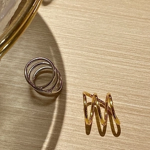 Minimalist multilayer spiral ring in gold and silver finish on a wooden background