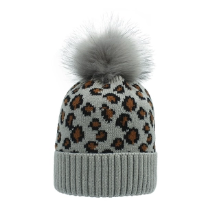 Detailed knit texture of leopard print winter hat with fluffy grey faux fur pom pom