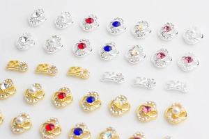 Detailed view of 520 nail charms with gold and silver bases, pearls and colorful rhinestones