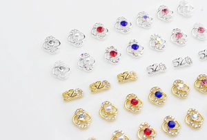 Macro detail of alloy nail charms featuring hollow lines, pearls, and 520 zircon designs