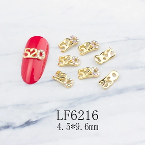 Macro detail of 520 gold alloy nail charms with colorful rhinestones on marble