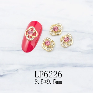 Detail of flower nail art charm with pink rhinestone and gold base on red nails