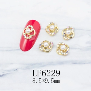 Detail of gold hollow flower nail art charm with white pearl and colorful rhinestones