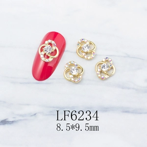 Detail of 8.5x9.5mm hollow flower alloy nail charm with central rhinestone and gold finish