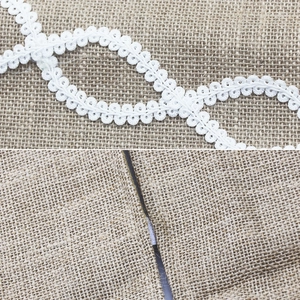 Détail de la bordure en dentelle blanche sur tissu de jute pour jupe de sapin de Noël