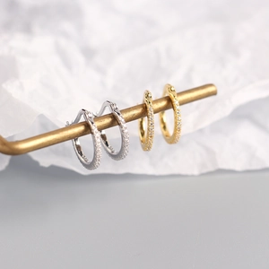 Detail view of gold and silver S925 sterling silver hoop earrings with colored diamonds