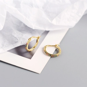 Macro shot of gold-plated hoop earrings featuring colorful rainbow zircon stones