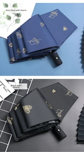 Detail of navy and black folding umbrellas with golden heart patterns and auto-open button