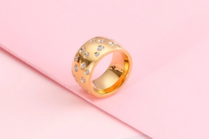 Detailed view of wide gold-plated ring with inlaid circular cubic zirconia stones