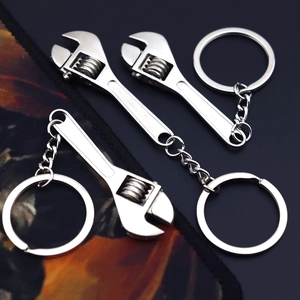 Three mini silver metal adjustable wrench keychains on a dark textured background