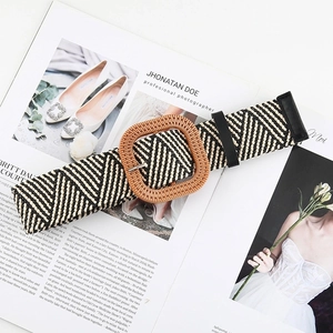 Detail of woven straw belt with black and beige V-pattern and square wooden buckle
