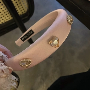 Close-up of pink padded headband featuring champagne gold rhinestone heart charms
