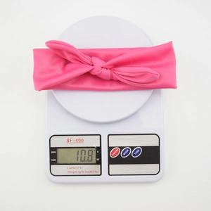 Close-up of bright pink elastic knotted headband for babies weighing 10.8g on a scale