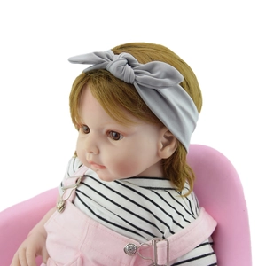 Detail showing grey knotted bow headband on a baby model with soft elastic fabric texture
