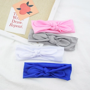 Flat lay of four elastic knot headbands in pink, grey, white, and blue fabric