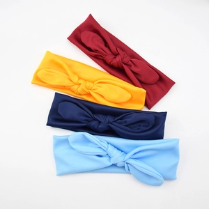 Flat lay of soft elastic baby headbands with knotted bows in red, yellow, and blue colors