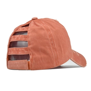 Detail of cross elastic bands on washed cotton ponytail baseball cap in brick red
