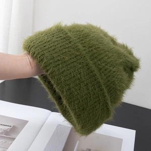 Close-up detail of soft moss green fuzzy knit beanie with thick long plush texture