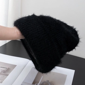 Detailed close-up of soft black fluffy knit beanie with warm plush furry texture