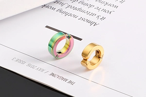 Détail de boucles d'oreilles clips minimalistes arc-en-ciel et dorées sur un magazine