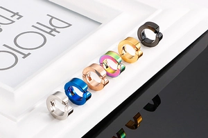 Gros plan de clips d'oreilles en acier inoxydable poli en six couleurs sur cadre blanc