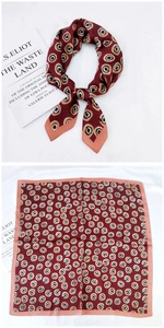 Gros plan d'un foulard carré en soie bordeaux avec motif géométrique et bords orange